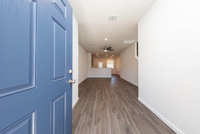 corridor featuring visible vents, baseboards, and wood finished floors