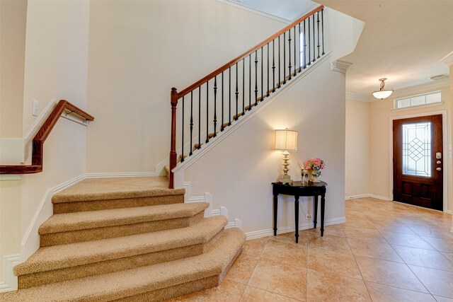 tiled entrance foyer featuring crown molding