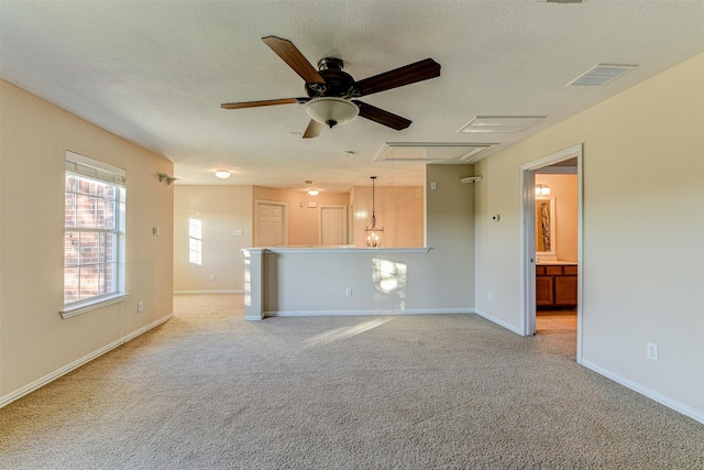 unfurnished living room with ceiling fan, light colored carpet, and a textured ceiling