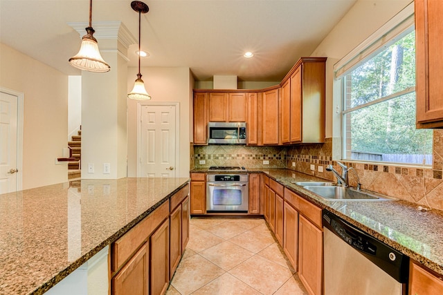 kitchen featuring hanging light fixtures, stone countertops, appliances with stainless steel finishes, and sink