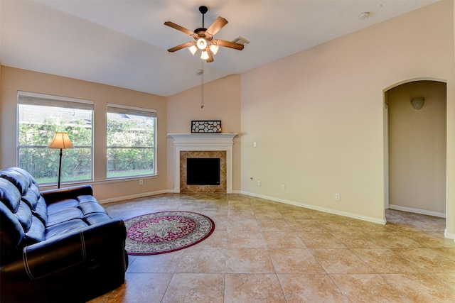 living room featuring lofted ceiling, a high end fireplace, ceiling fan, and light tile patterned flooring