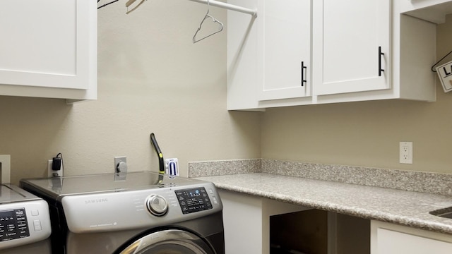 clothes washing area featuring washer and clothes dryer and cabinets