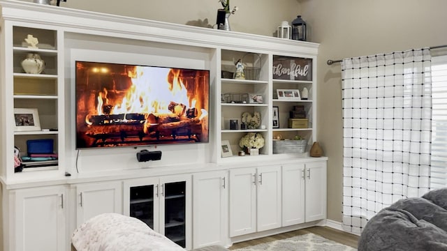 bar with white cabinets, a fireplace, and wood-type flooring