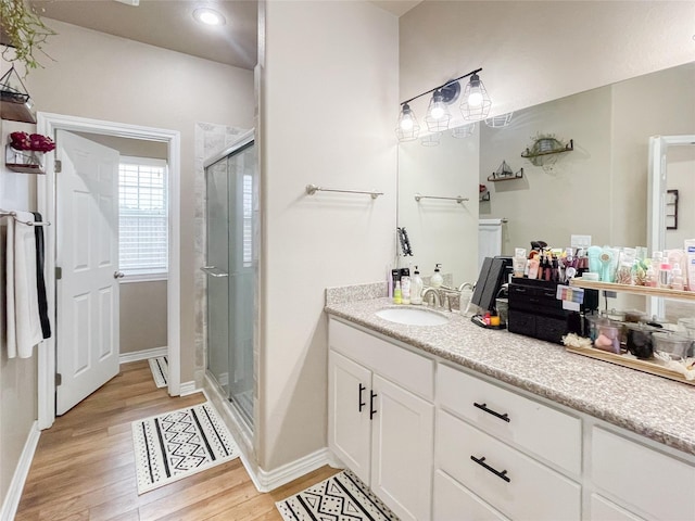 bathroom with walk in shower, vanity, and wood-type flooring