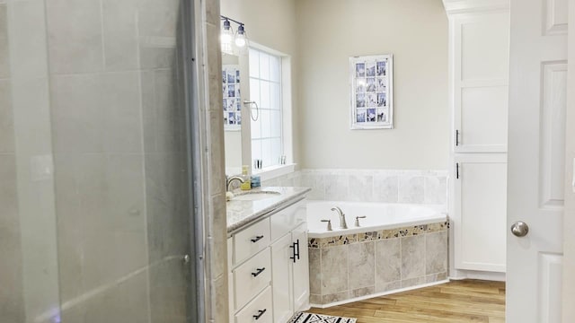 bathroom with vanity, hardwood / wood-style floors, and tiled tub