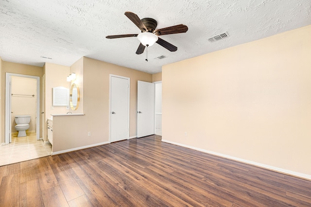 1727 Oakwell Ln, Katy, TX 77449 - unfurnished bedroom with wood finished floors, baseboards, a textured ceiling, ensuite bathroom, and ceiling fan