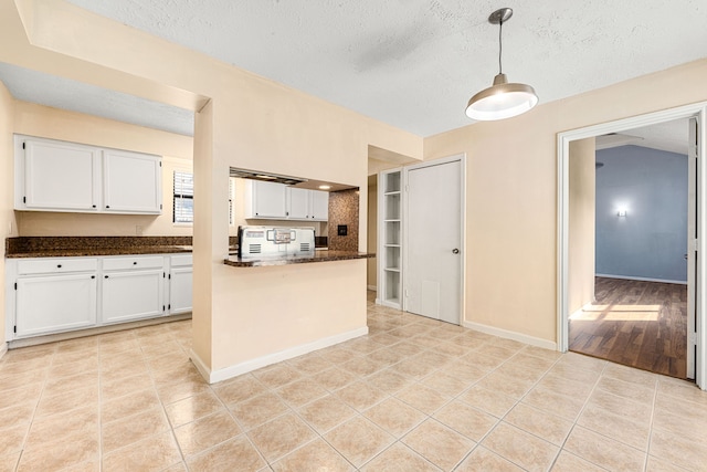 kitchen featuring hanging light fixtures, light tile patterned floors, white cabinets, and a textured ceiling