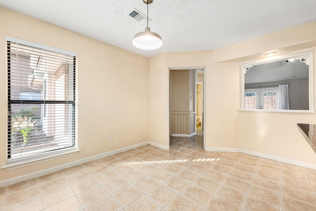 unfurnished room with light tile patterned floors and a textured ceiling