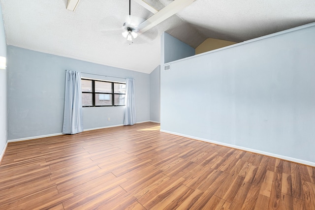 unfurnished room featuring wood-type flooring, a textured ceiling, and vaulted ceiling