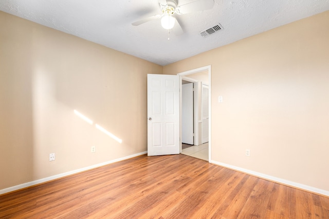 empty room featuring ceiling fan, light hardwood / wood-style floors, and a textured ceiling