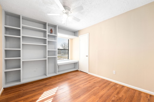 unfurnished room with ceiling fan, wood-type flooring, and a textured ceiling