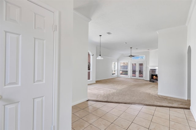 unfurnished living room featuring crown molding, vaulted ceiling, light colored carpet, and ceiling fan