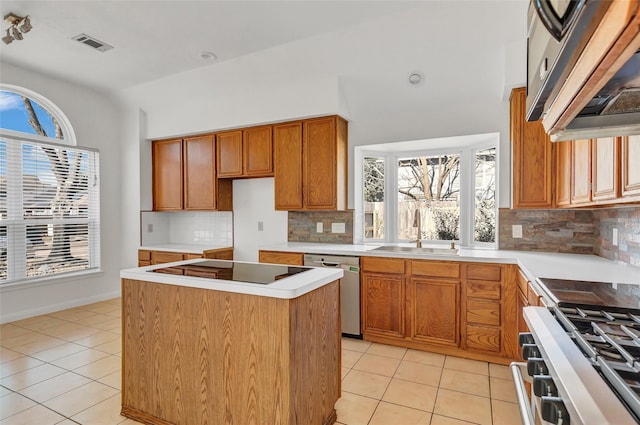 kitchen with sink, a center island, light tile patterned floors, appliances with stainless steel finishes, and backsplash