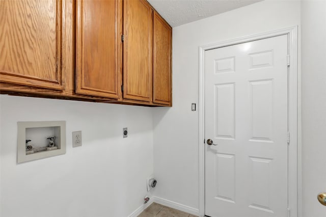 laundry area with light tile patterned flooring, cabinets, hookup for a washing machine, electric dryer hookup, and a textured ceiling