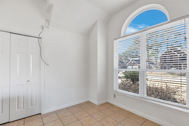 unfurnished room featuring plenty of natural light, light tile patterned floors, and lofted ceiling