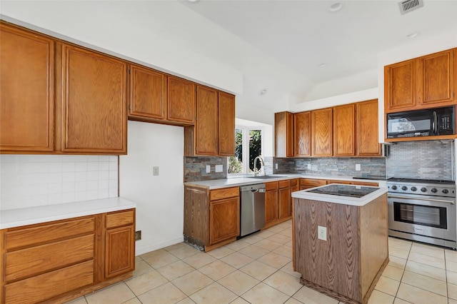 kitchen featuring tasteful backsplash, lofted ceiling, a center island, light tile patterned floors, and stainless steel appliances