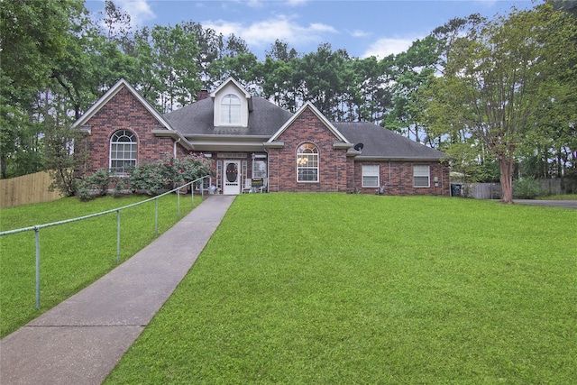 view of front of property with brick siding, fence private yard, a front yard, and a shingled roof