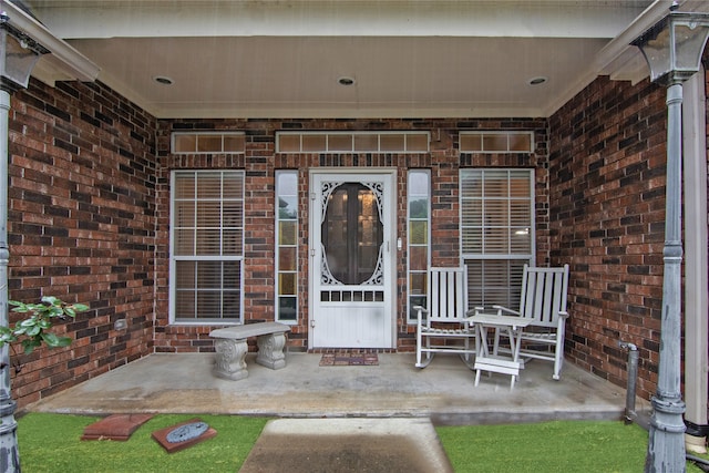 property entrance with covered porch and brick siding