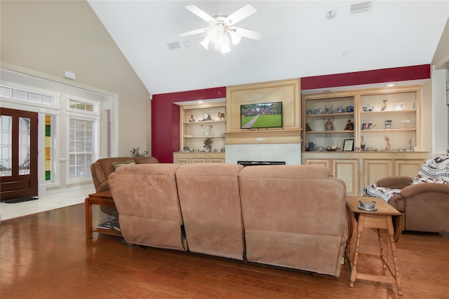 living room featuring built in shelves, wood-type flooring, a tile fireplace, and ceiling fan