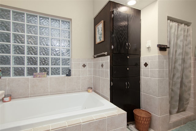 bathroom featuring shower with separate bathtub and tile walls