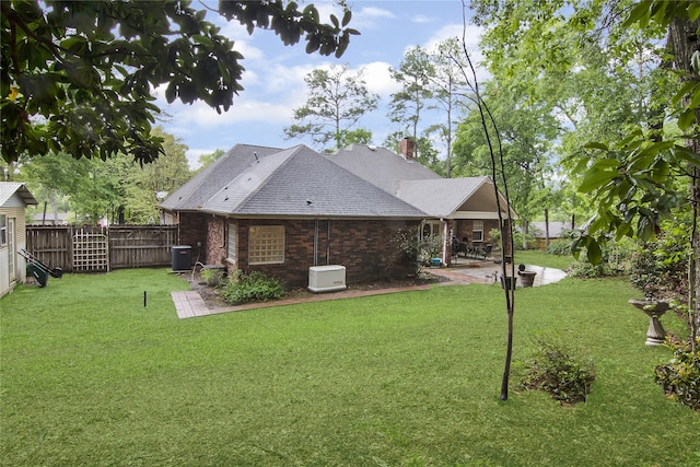 back of property with a fenced backyard, a chimney, a yard, a patio area, and brick siding