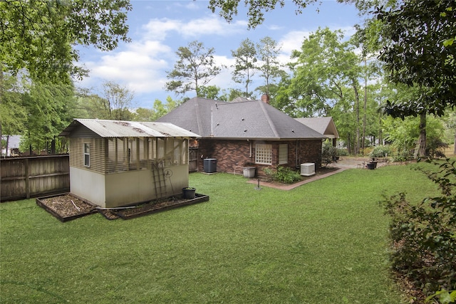 back of house featuring cooling unit, an outbuilding, and a lawn