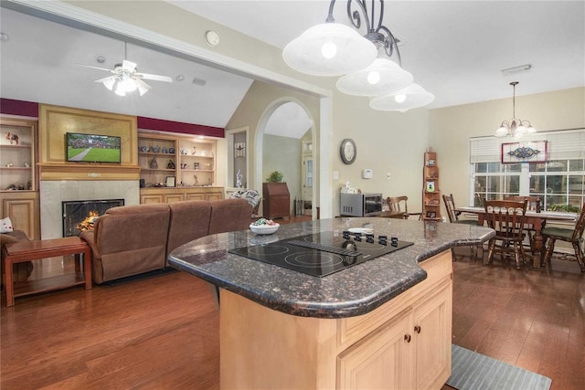 kitchen with arched walkways, black electric cooktop, vaulted ceiling, dark wood-style floors, and a tiled fireplace