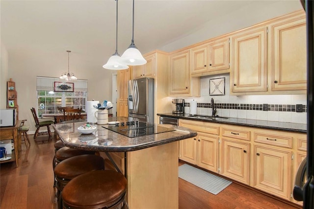 kitchen with a breakfast bar, pendant lighting, sink, a center island, and black appliances