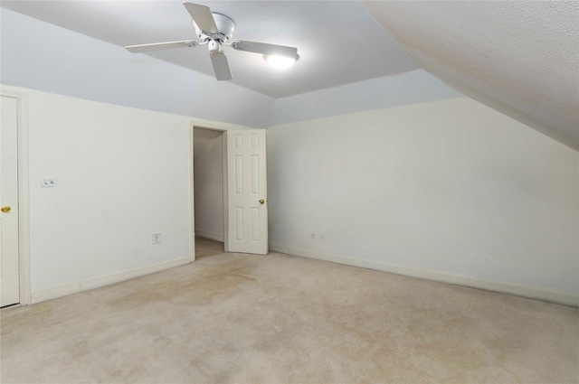 unfurnished bedroom featuring baseboards, ceiling fan, carpet, vaulted ceiling, and a textured ceiling