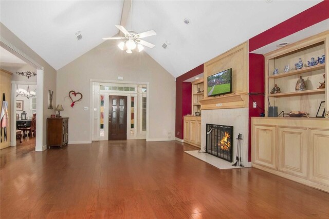 living room with ceiling fan with notable chandelier, built in features, wood finished floors, and a premium fireplace
