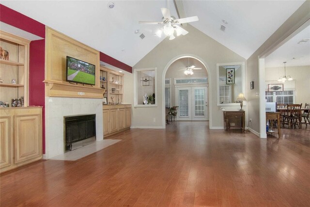 unfurnished living room with built in features, wood finished floors, baseboards, a fireplace, and ceiling fan with notable chandelier