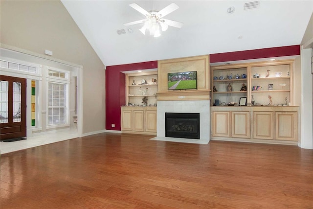 unfurnished living room featuring light wood finished floors, visible vents, ceiling fan, built in features, and a fireplace