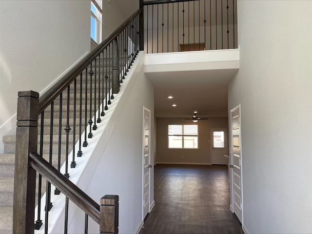 staircase with ceiling fan, wood-type flooring, and a high ceiling