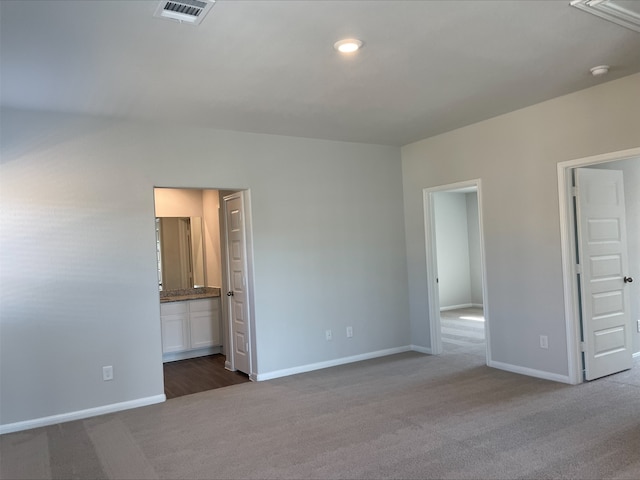 unfurnished bedroom with dark colored carpet and connected bathroom