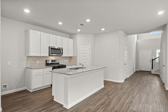 kitchen with visible vents, a kitchen island with sink, stainless steel appliances, white cabinetry, and a sink