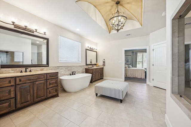 bathroom featuring tile walls, tile patterned flooring, vanity, a notable chandelier, and a tray ceiling