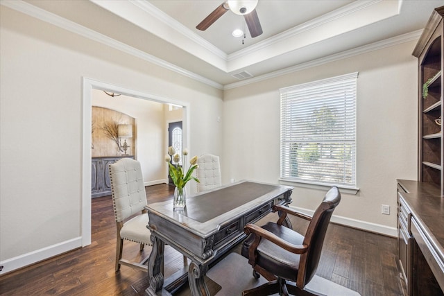 office space featuring a raised ceiling, crown molding, dark wood-type flooring, and ceiling fan