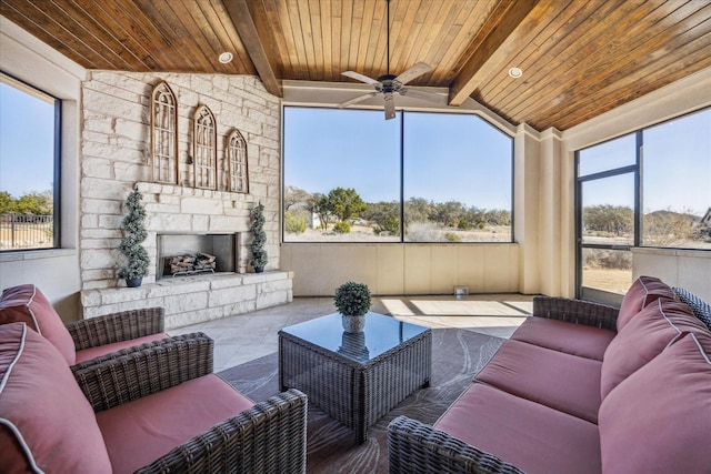 sunroom / solarium with lofted ceiling with beams, ceiling fan, wooden ceiling, and an outdoor stone fireplace