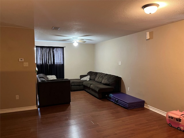 living room featuring ceiling fan, dark hardwood / wood-style floors, and a textured ceiling