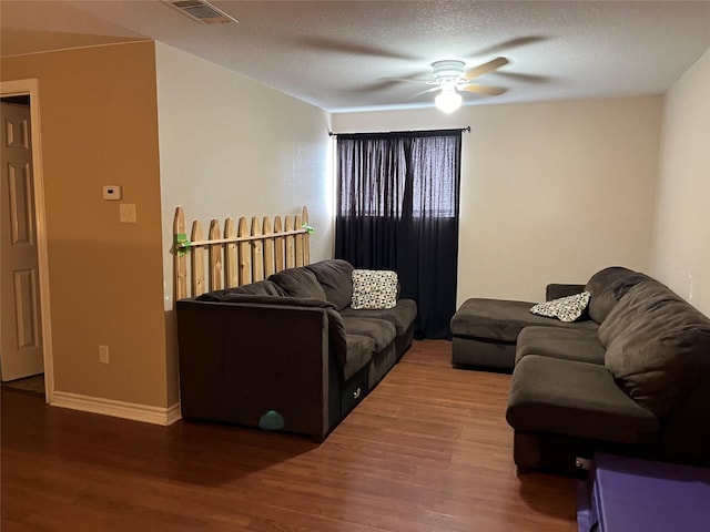 living room featuring ceiling fan, a textured ceiling, and dark hardwood / wood-style flooring