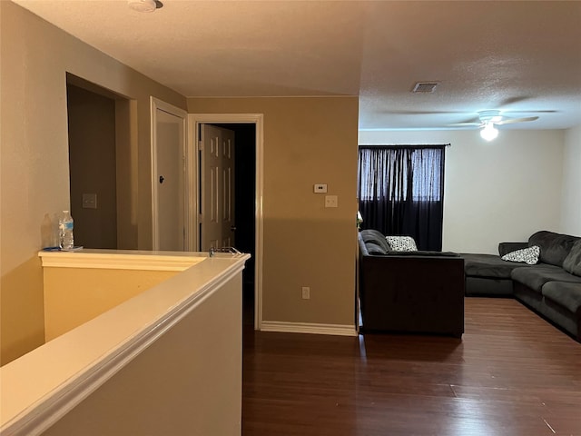 living room with dark wood-type flooring, ceiling fan, and a textured ceiling