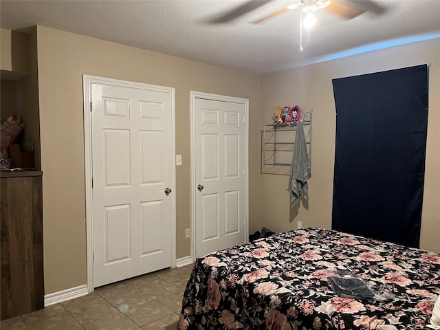 bedroom featuring ceiling fan, light tile patterned floors, and a textured ceiling