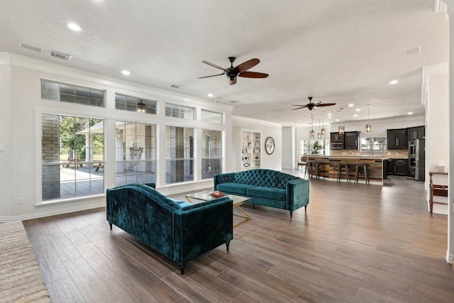 living room featuring crown molding, dark hardwood / wood-style floors, ceiling fan, and a textured ceiling