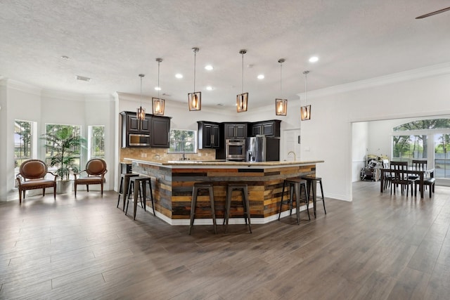 bar featuring decorative light fixtures, stainless steel appliances, and a healthy amount of sunlight