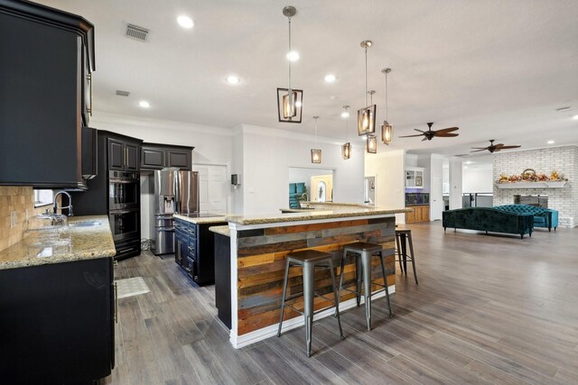 kitchen featuring sink, a breakfast bar area, hanging light fixtures, a center island, and light stone counters