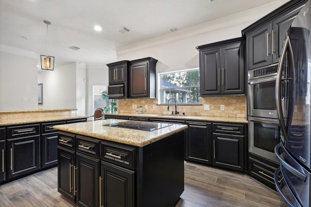 kitchen featuring pendant lighting, sink, backsplash, a center island, and black electric cooktop