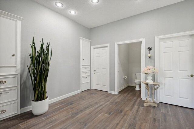 bedroom featuring connected bathroom, dark hardwood / wood-style floors, and a textured ceiling