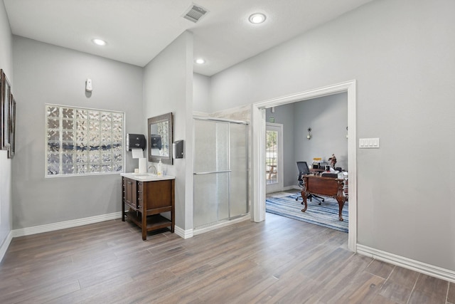 interior space with a shower with door, vanity, and hardwood / wood-style floors