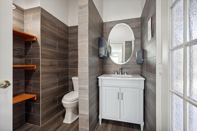 bathroom with vanity, tile walls, and toilet