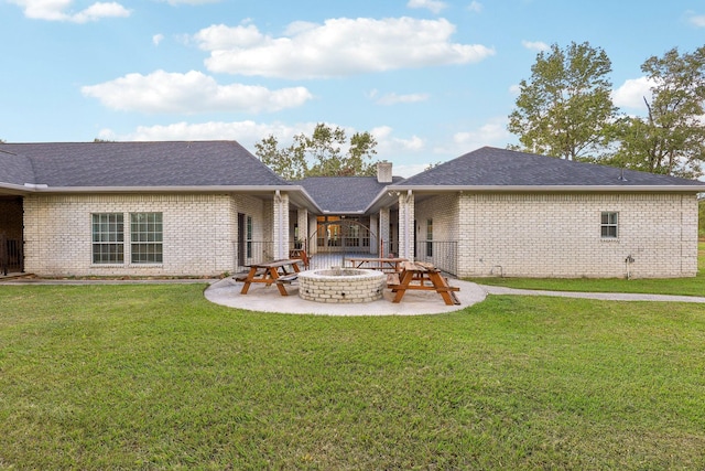 back of property with an outdoor fire pit, a patio area, and a lawn